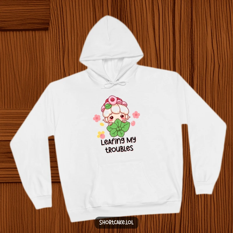 Funny Shortcake Hoodie: A shortcake character peeks from behind a large mint leaf with a grin, offering cozy dessert cheer.