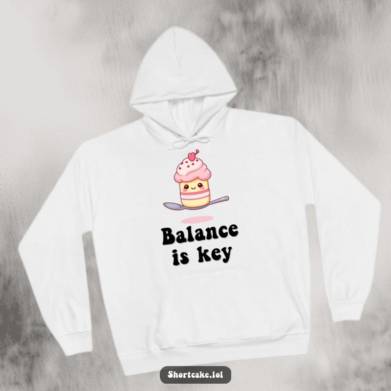 Funny shortcake winking on a spoon hoodie, a dessert character balancing precariously, offering warmth and humor.
